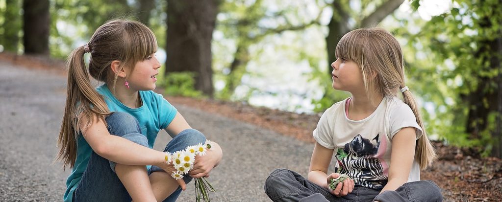 Two girls sitting in the road talking